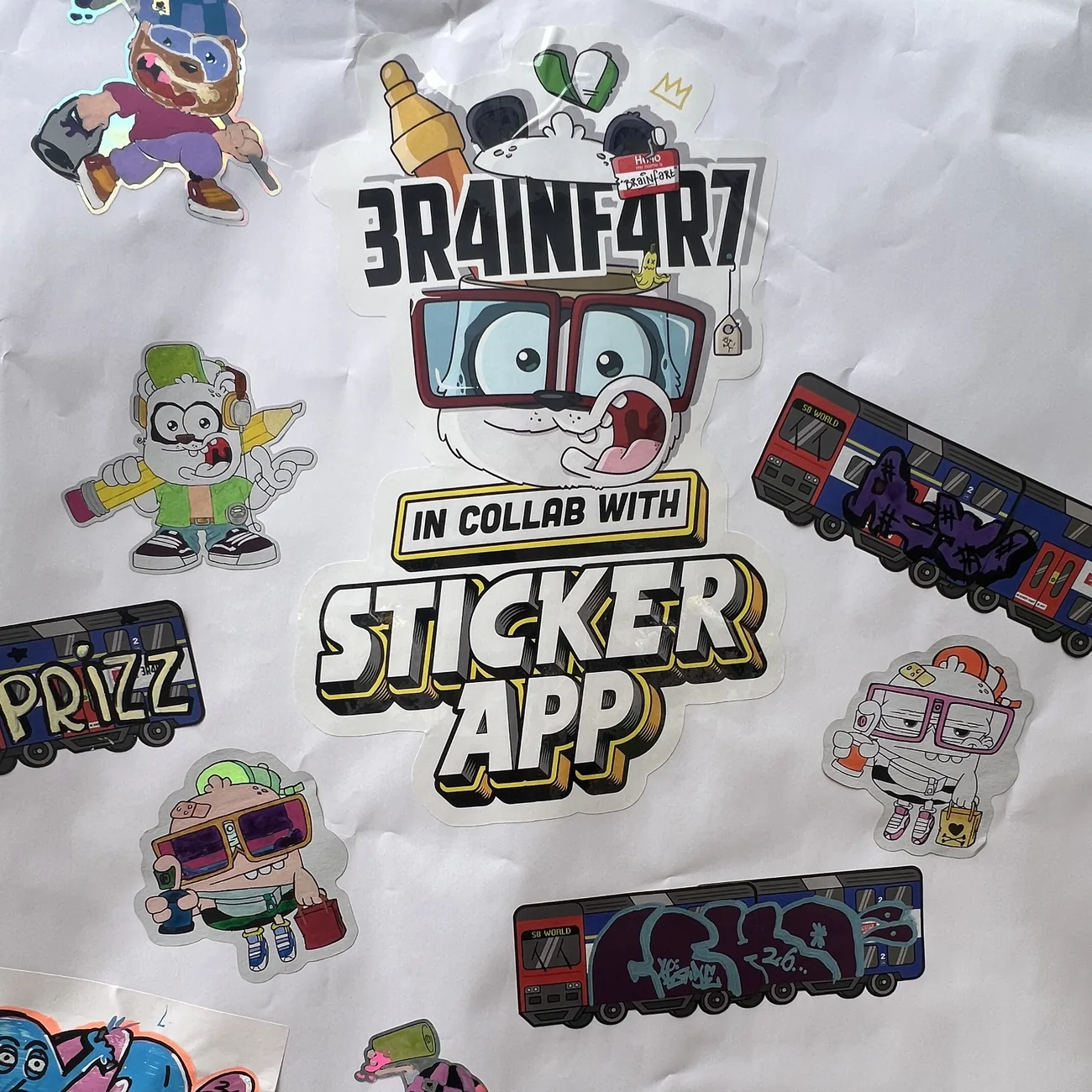 Wall covered in hand-colored Brainfart x StickerApp die-cut stickers and S8 World train labels with graffiti tags