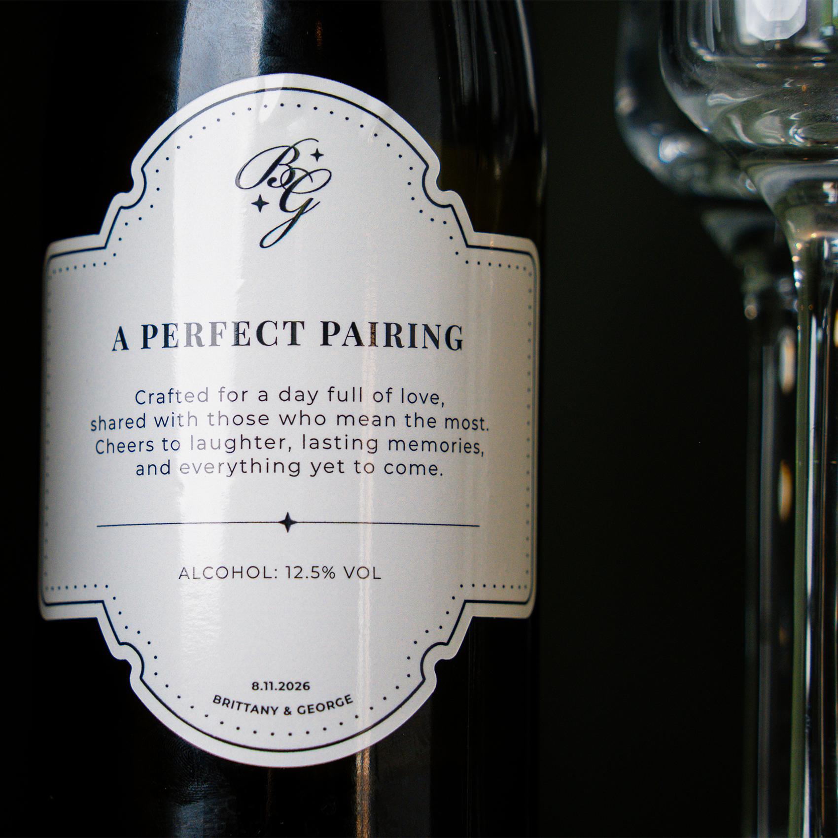 Close-up of a custom wine bottle label with elegant typography reading “A Perfect Pairing,” including a wedding message, alcohol percentage, and the names Brittany & George with a wedding date.