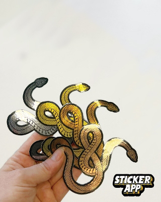 Hand holding brushed aluminum snake stickers in silver, gold, rose gold and bronze tones
