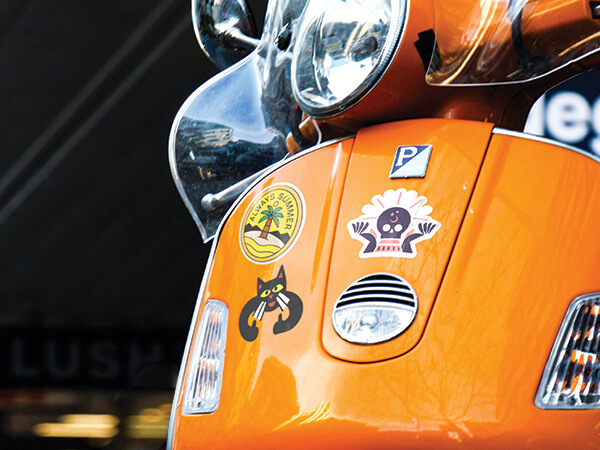A close up of a moped with die cut custom stickers on it.